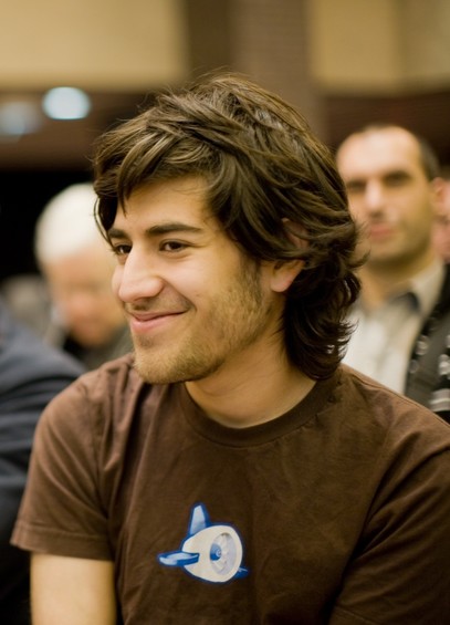 Aaron Swartz wearing a brown tee shirt emblazoned with what appears to be a white turbofan engine with blue vertical stabilizer and horizontal wings attached.